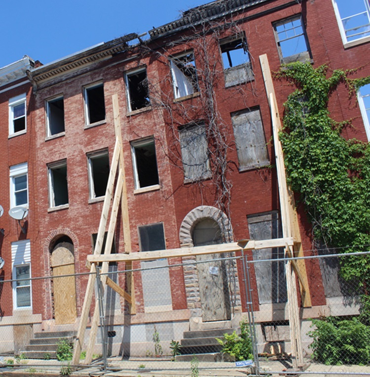 Brick homes in need of renovation with plants and scaffolding holding the walls up.